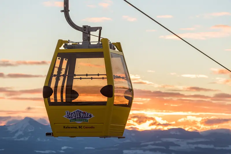 A yellow Big White gondola cabin against a golden sunset